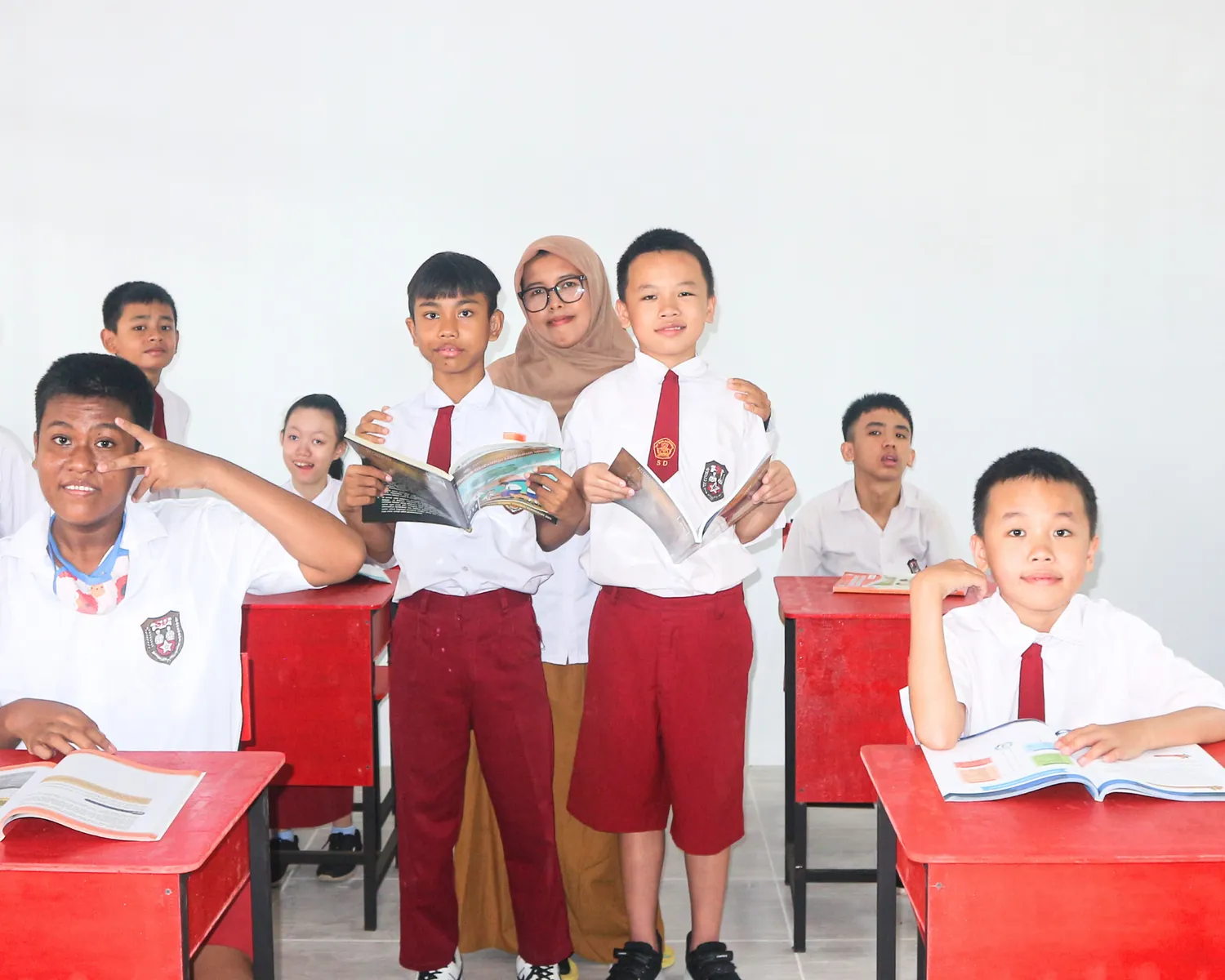 Siswa SDLB berdiri bersama guru sambil memegang buku